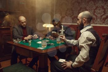Male player cheating in poker at gaming table, casino. Games of chance addiction, risk, gambling house. Men leisures with whiskey and cigars