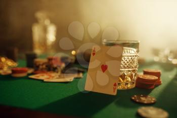 Poker concept, ace of hearts on gaming table closeup, whiskey and cigar in casino, nobody. Games of chance. Gambling house business