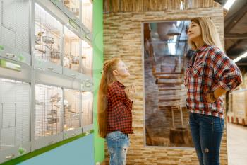 Daughter persuades her mother to buy a bird in pet store. Woman and little child buying equipment in petshop, accessories for domestic animals