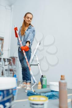 Female house painter with paint roller. Home repair, laughing woman doing appartment renovation, room decoration renovating