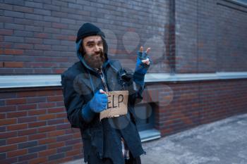 Beggar man and help sign on city street. Poverty is a social problem, homelessness and loneliness, alcoholism and drunk addiction