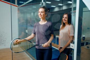 Two smiling female squash players poses in locker room. Youth on training, active sport hobby, fitness workout for healthy lifestyle