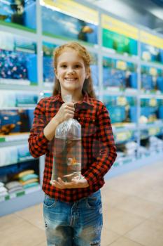 Happy little girl holds goldfish and makes a wish, pet store. Child buying equipment in petshop, accessories for domestic animals