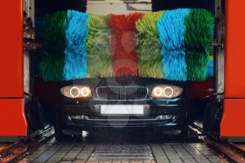 Auto in foam on automatic car wash with colorful brush, nobody. Vehicle cleaning service or business, express carwash station