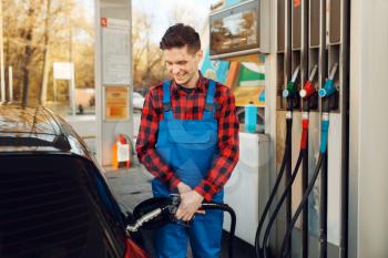 Male worker in uniform fuels car on gas station, fuel filling. Petrol fueling, gasoline or diesel refuel service