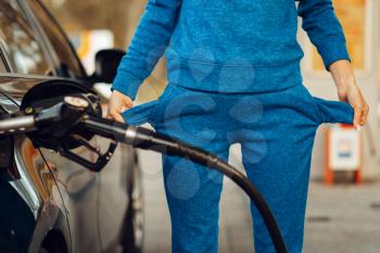 Female person with empty pockets on gas station, fuel filling. Petrol fueling, gasoline or diesel refuel service, high price on petroleum