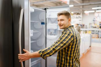 Man choosing refrigerator in electronics store. Male person buying home electrical appliances in market