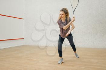 Female player with squash racket in action. Girl on game training, active sport hobby on court