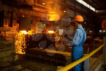Master steelmaker in helmet at furnace with liquid metal, steel factory, metallurgical or metalworking industry, industrial manufacturing of iron production on mill