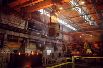Crane with bucket of liquid metal on steel factory, metallurgical or metalworking industry, industrial manufacturing of production on mill