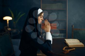 Young nun in a cassock prays crossed her arms. The sister in the monastery, religion and faith, religious person