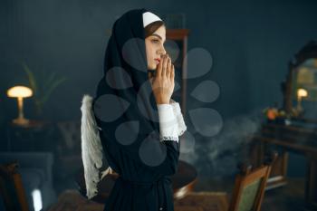 Young nun in a cassock prays crossed her arms. The sister in the monastery, religion and faith