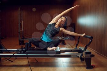 Fit girl in sportswear, pilates training on exercise machine in gym. Fitness workuot in sport club. Athletic female person, aerobics indoor, body stretching