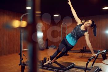 Slim girl in sportswear, pilates training on exercise machine in gym. Fitness workuot in sport club. Athletic female person, aerobics indoor, body stretching