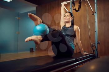 Slim woman in sportswear, pilates training with ball on exercise machine in gym. Fitness workuot in sport club. Athletic female person, aerobics indoor, body stretching