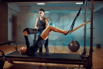 Slim girl in sportswear and instructor, pilates training with ball on exercise machine in gym. Fitness workuot in sport club. Athletic female person, aerobics indoor, body stretching