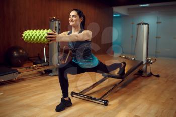Sporty woman in sportswear, pilates training with roll on exercise machine in gym. Fitness workuot in sport club. Athletic female person, aerobics indoor, body stretching