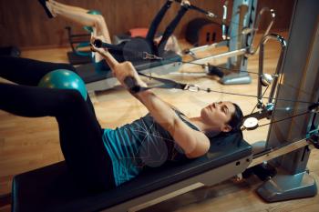 Two women in sportswear, pilates training with balls on exercise machines in gym. Fitness workuot in sport club. Athletic female person, aerobics indoor, body stretching