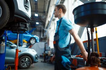 Repairman in uniform fix vehicle on lift, car service station. Automobile checking and inspection, professional diagnostics and repair