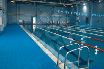 Sport swimming pool interior, nobody. Empty poolside with tracks and ladder, blue water and tile, public place for healthy lifestile