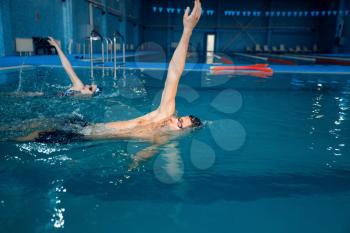 Male swimmer swims in the pool. Man and woman in the water, sport swimming skill training, motion view, workout before competition