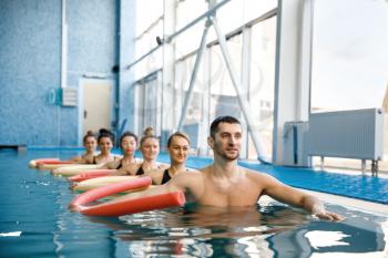 Male instructor and female swimmers group, aqua aerobics training in the pool. Man and women in the water, sport swimming fitness workout