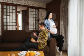 Husband and his pregnant wife with belly relaxing at home. Pregnancy, prenatal period. Expectant mom and dad are resting, health care