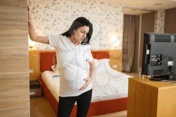 Pregnant woman with belly felt contractions in bedroom at home. Pregnancy, calm in prenatal period. Expectant mom resting, healthy lifestyle