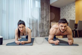 Morning fitness workout of family couple at home. Active man and woman in sportswear doing push up exercise in their house, healthy lifestyle, physical culture