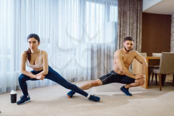 Morning aerobic workout of love couple at home. Active man and woman in sportswear doing push up exercise in their house, healthy lifestyle, physical culture