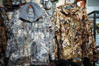 Winter uniform, showcase in gun shop, nobody. Euqipment for hunters on stand in weapon store, hunting and military hobby