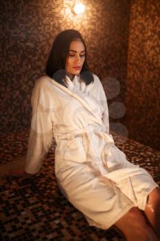 Woman sitting on a hot stone in turkish bath, hamam, sauna. Skin and body care