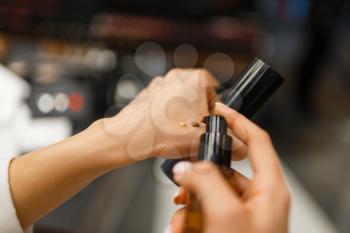 Woman choosing concealer tone in cosmetics store. Buyer in luxury beauty shop salon, female customer in fashion market