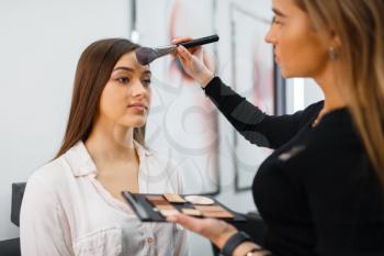 Cosmetician with brush and woman, client in cosmetics store. Luxury beauty shop salon, female customer and beautician in fashion market