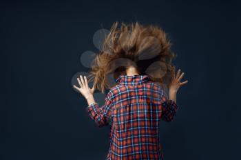 Little girl against powerful airflow in studio, developing hairstyle effect. Children and wind, kid isolated on dark background, child emotion