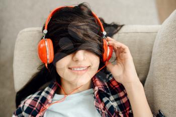 Woman with her hair on eyes enjoys listen to music in headphones. Pretty lady in earphones relax in the room, female sound lover resting
