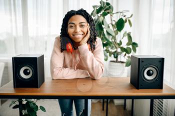 Happy woman sitting between two audio speakers and listening to music. Pretty lady relax in the room, female sound lover resting