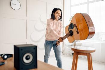Crazy woman breaks the guitar near audio speaker, the music is maddening. Pretty lady relax in the room, female sound lover resting