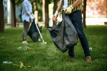 People collects garbage in a bag in park, volunteering. Male person cleans forest, ecological restoration, eco lifestyle, trash collection and recycling, ecology care, environment cleaning