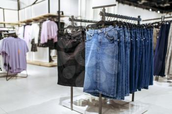 Clothes, denim skirts collection on racks in clothing store, nobody. Fashion shop or boutique interior, garment on hangers in showroom