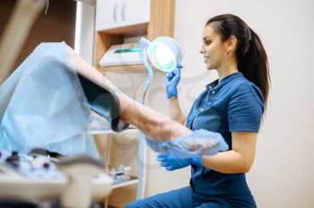 Female gynecologist in gloves and uniform at workplace and patient in chair. Gynecological examination in clinic, gynecology diagnostic or consultation, exam
