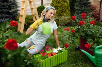 Smiling woman with spray watering flowers in the garden. Female gardener takes care of plants outdoor, gardening hobby, florist lifestyle and leisure