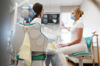 Female dentist shows to patient x-ray of teeth, stomatology clinic. Doctor in uniform, medical worker, stomatologist, medicine and health, professional dental mouth care and hygiene, dentistry