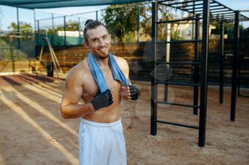 Smiling man with muscular body, street workout. Fitness training on sports ground in summer day, male person pumps muscles, active urban lifestyle