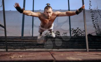 Athletic man doing push-up exercise with jumps, street workout, crossfit. Fitness training on sports ground outdoor, male person pumps muscles, active lifestyle