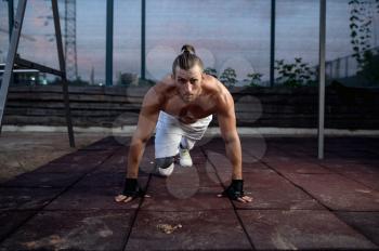 Athletic man doing push-up exercise on sunset, street workout, crossfit. Fitness training on sports ground outdoor, male person pumps muscles, active urban lifestyle