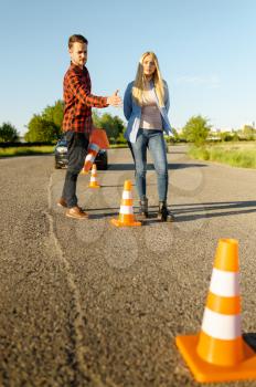 Male instructor and woman, traffic cones on road, driving school. Man teaching lady to drive vehicle. Driver's license education
