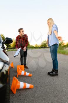 Sad female student in car and instructor, all traffic cones are downed, lesson in driving school. Man teaching lady to drive vehicle. Driver's license education