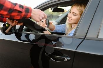 Instructor with checklist gives the keys to student in car, examination or lesson in driving school. Man teaching lady to drive vehicle, exam. Driver's license education
