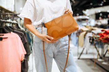 Woman holds handbag in clothing store. Female person shopping in fashion boutique, shopaholic, shopper looking on garment
